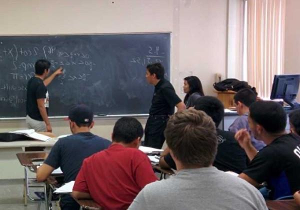 peer advisor with students writing on chalkboard