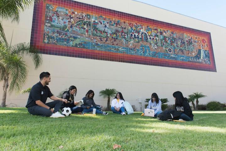 学生们坐在营地草坪前的瓷砖马赛克上