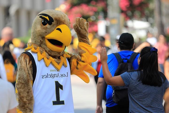 Eddie the Eagle high fives student on walkway